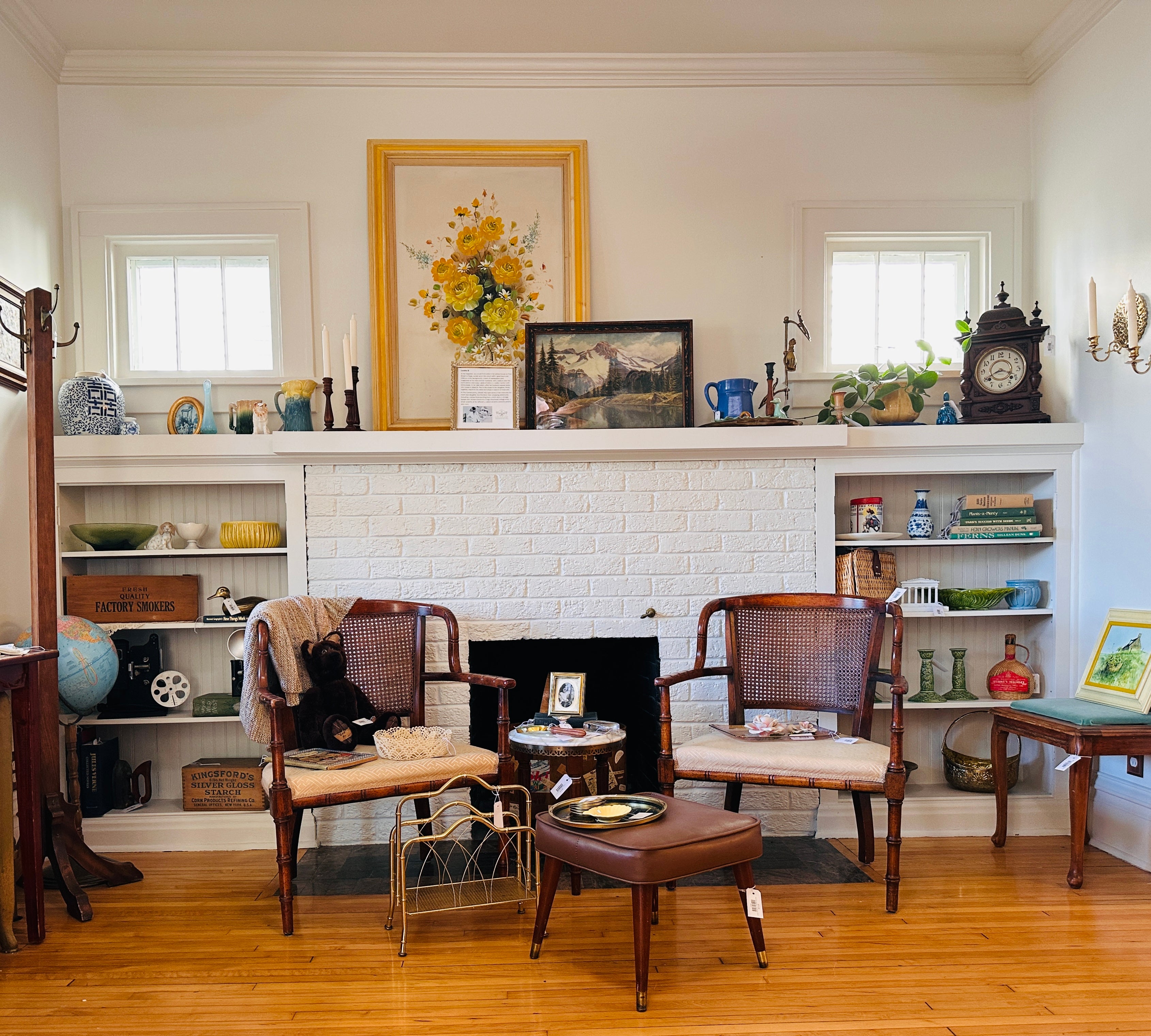 Living room with white brick fireplace, wooden chairs, and decorative items.