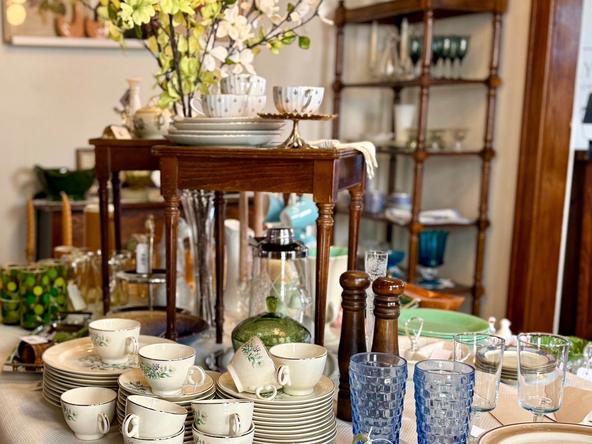 Dining room with a table set with plates, cups, and glasses, and a wooden sideboard in the background.